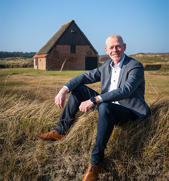 Makelaar van Makelaardij Eelman in de duinen van Texel met karakteristieke Texelse stolp op de achtergrond