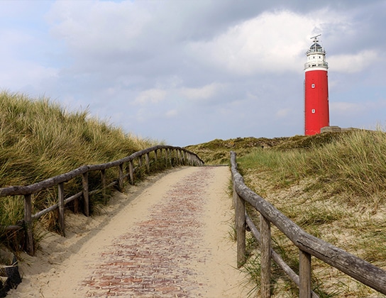 Duinpad op Texel met zicht op de iconische rode vuurtoren