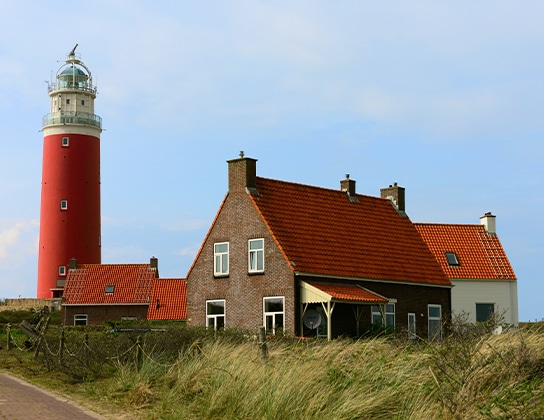 Woning bij de vuurtoren van Texel met rode daken in de duinen